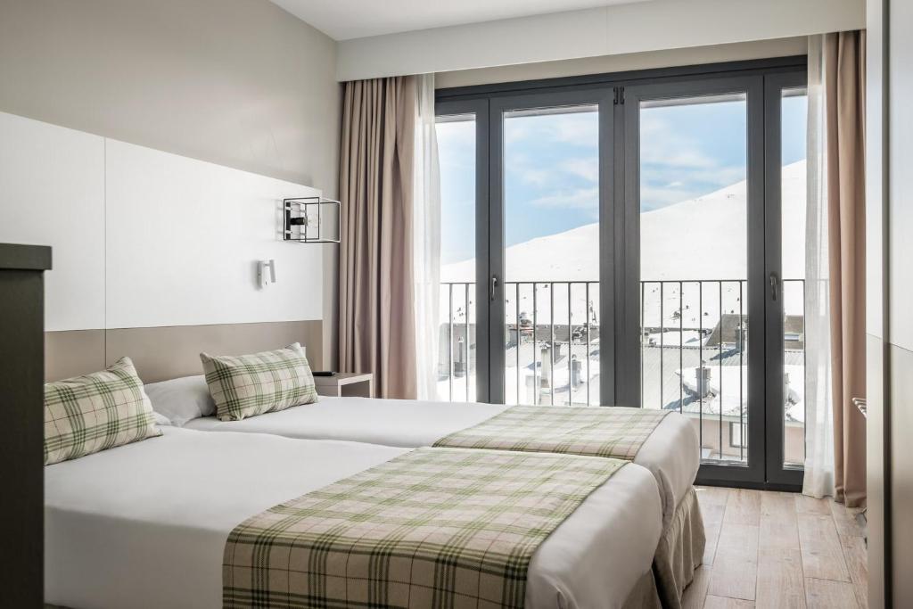 a hotel room with two beds and a large window at Estival Caribou Apartments in Pas de la Casa