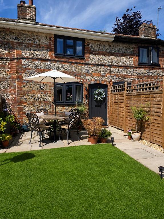 a patio with a table and an umbrella in a yard at Idyllic period cottage, Ramsbury, Nr Marlborough in Ramsbury