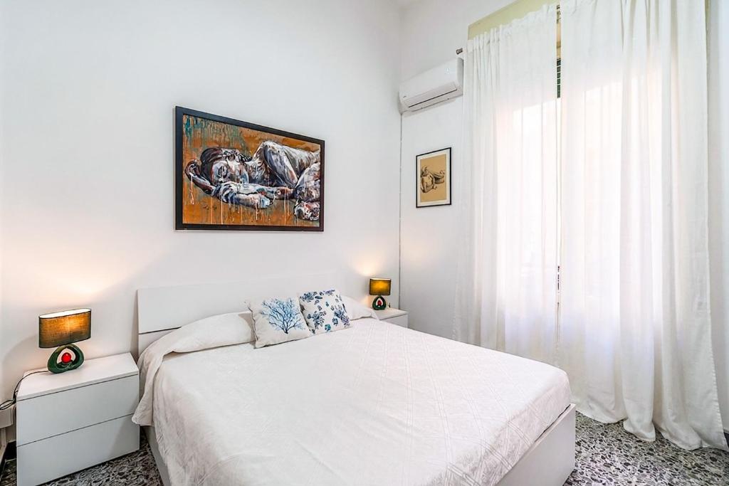 a white bedroom with a bed and a painting on the wall at Al Portico in Avola