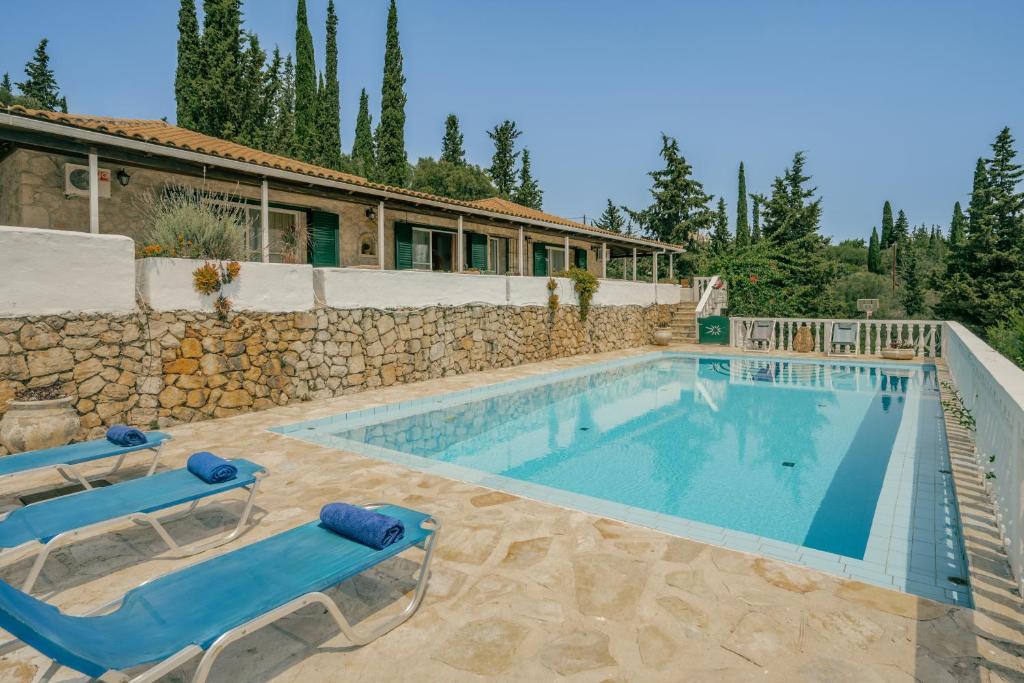 a pool with two lounge chairs and a house at Sunrise Stone Villa in Agios Nikolaos