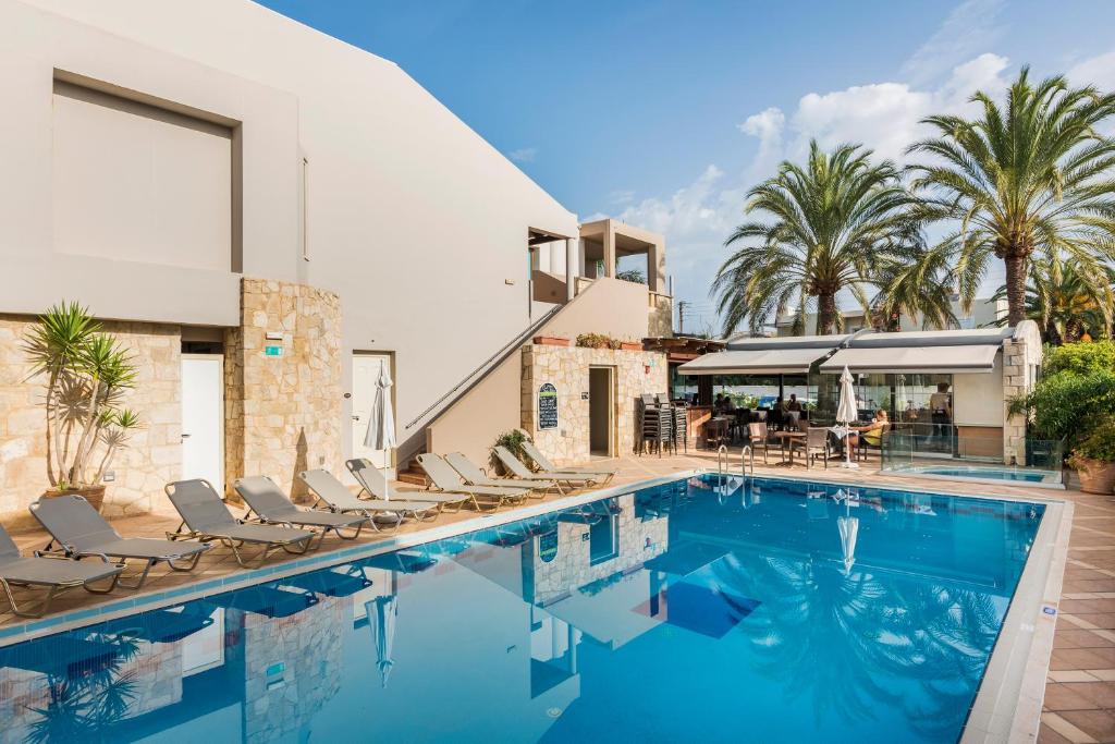 a swimming pool with chairs and a house at Elotis Suites in Agia Marina Nea Kydonias