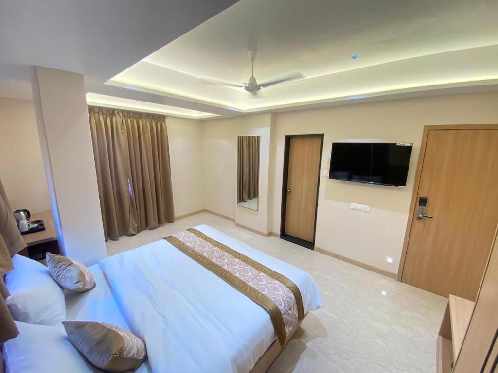 a hotel room with two beds and a flat screen tv at Hotel Banyan Crest in Solapur