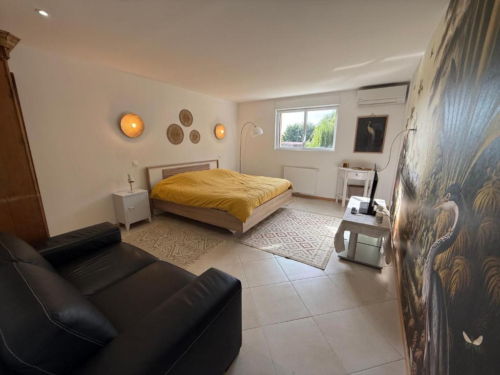 a bedroom with a bed and a couch in it at Le Refuge du Saule in Saint-Aubin-de-Locquenay