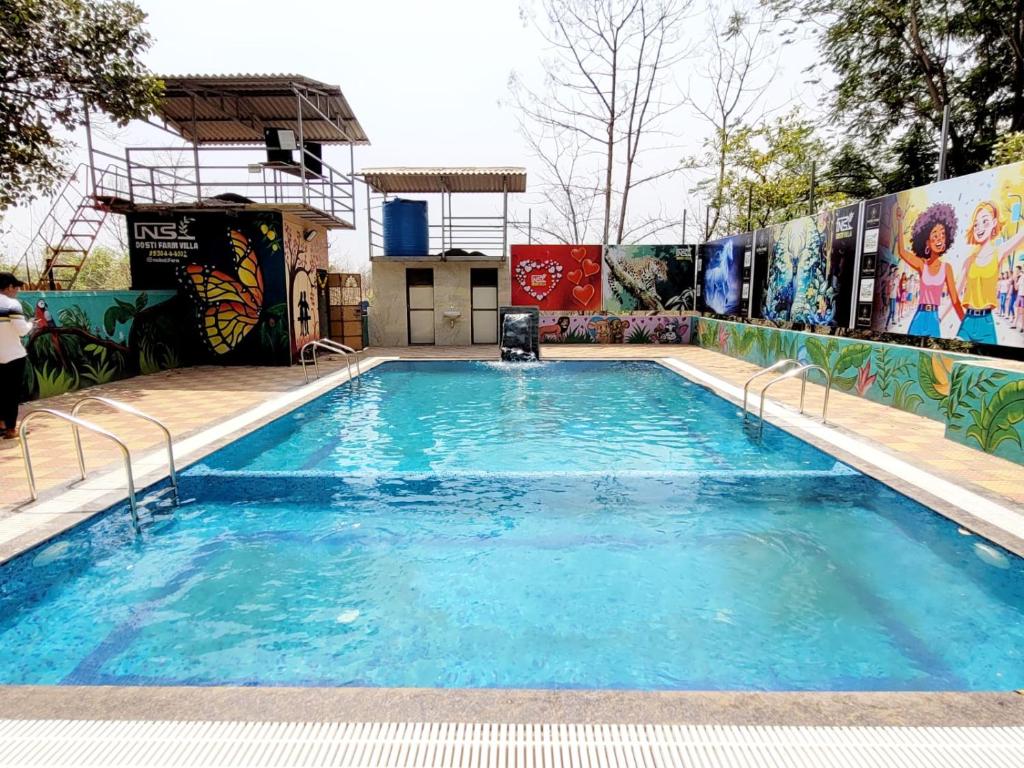 a large swimming pool with blue water at NS Dosti By Glitz Cottage in Agashi