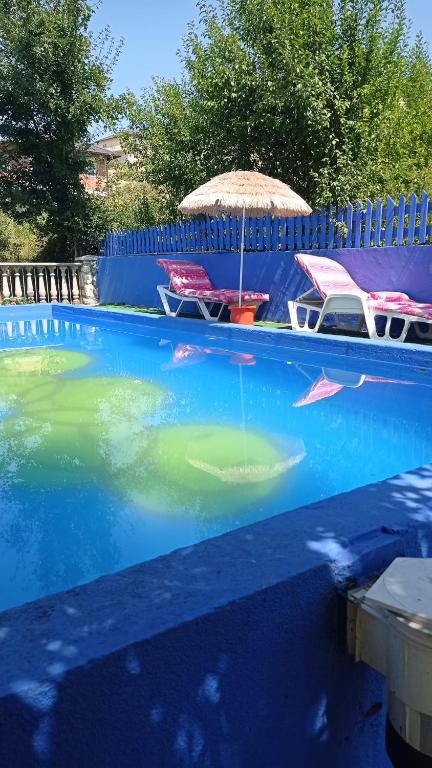 a swimming pool with chairs and an umbrella in the water at Soba za vise osoba in Ilijaš