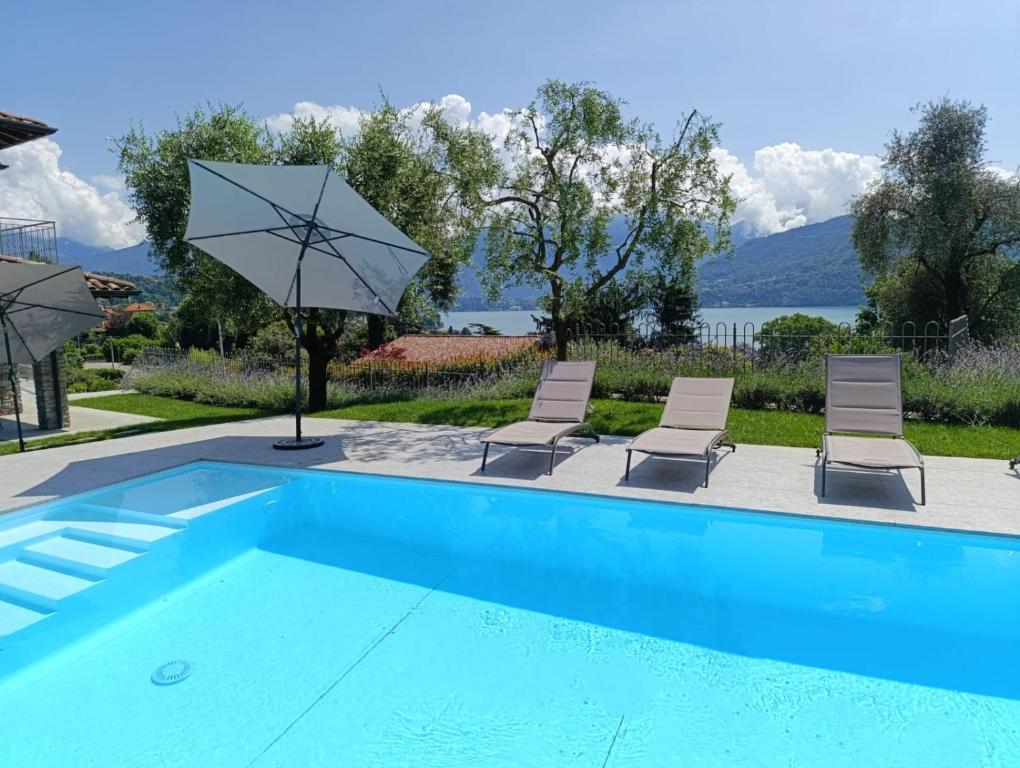 a swimming pool with two chairs and umbrellas at Design Villa in Tremezzina Villarnona Lake Como in Mezzegra