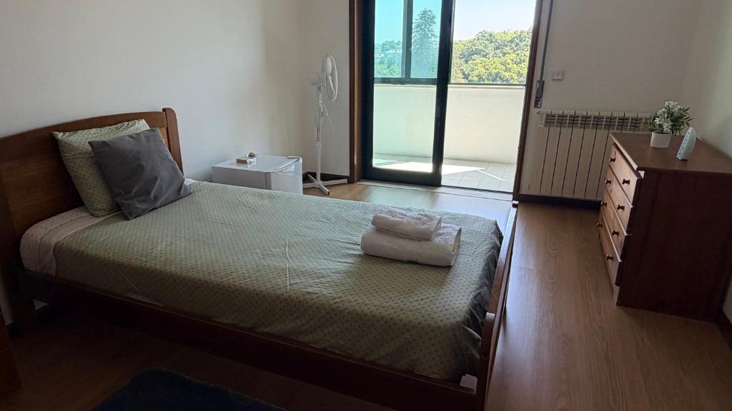 a bedroom with a bed and a dresser and a window at Quarto de Solteiro com varanda centro de Viseu in Viseu