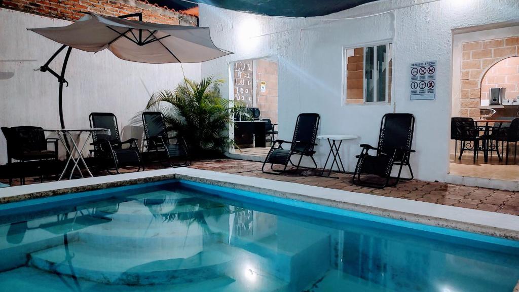 a swimming pool with chairs and a table and an umbrella at KingsLanding in Morelos