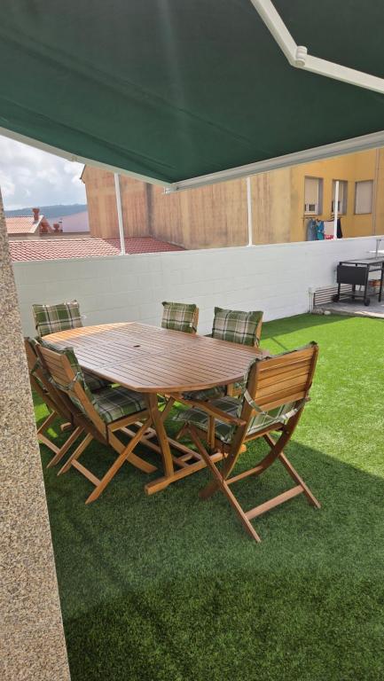 a wooden table and chairs with a green canopy at Casa del Arenal - Laxe in Laxe