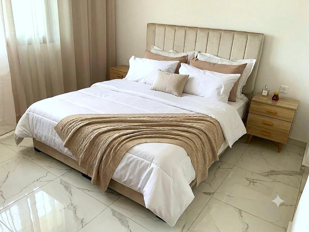 a bedroom with a large white bed with a wooden headboard at Un moment d'évasion in Rabat