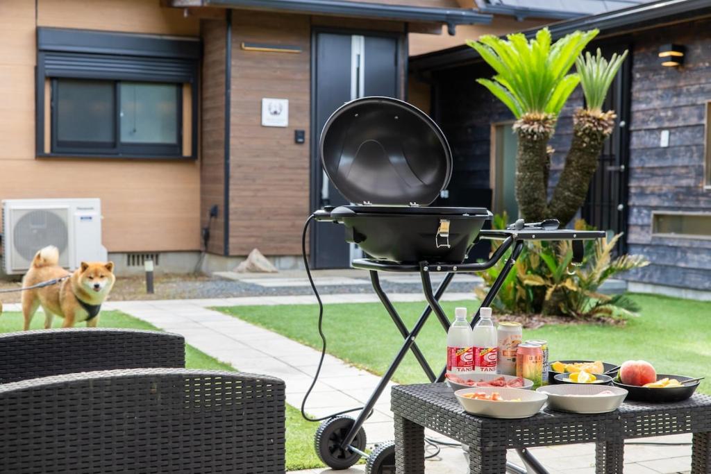 a barbecue grill on a table with a dog in the background at 愛犬と泊まれる一棟貸しviilaはBBQグリル無料利用可能サーフィンや釣りの拠点として in Kashima