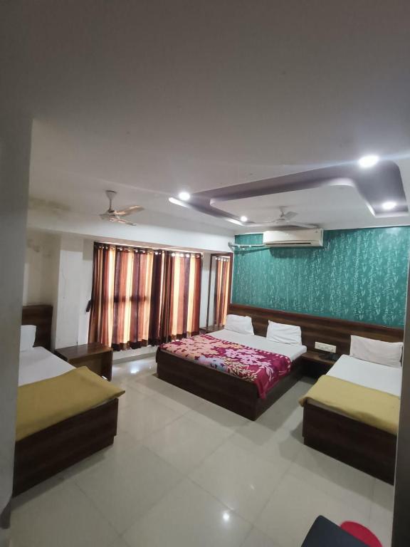 a bedroom with two beds and a green wall at Hotel Apex in Mahesāna