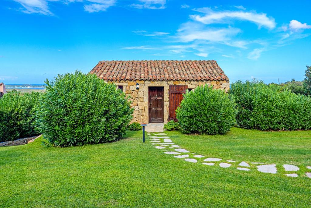 a small stone building with a door in the grass at Domus de pedra in Marina di Portisco