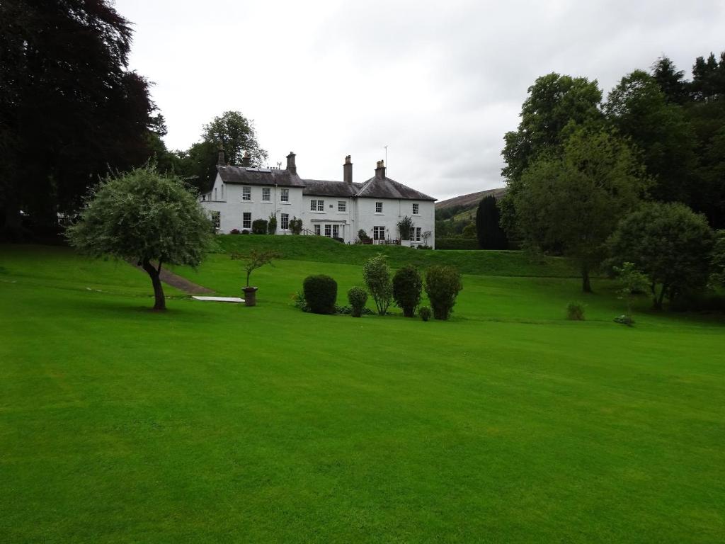 Elibank House B&B في Walkerburn: منزل أبيض فوق حقل أخضر