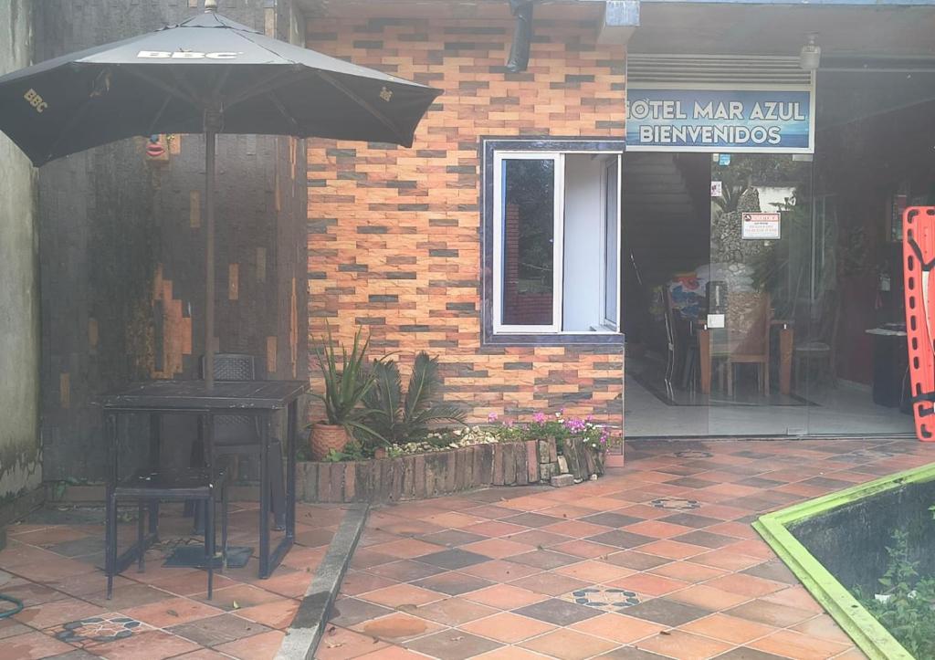 a table with an umbrella in front of a building at Hotel Mar Azul in Acacías