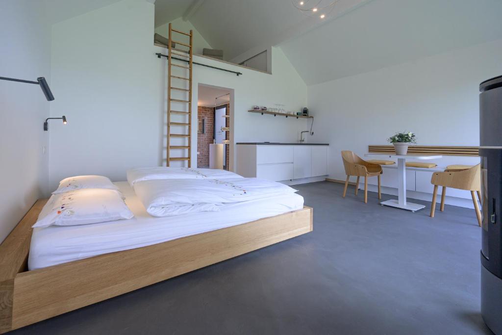 a bed in a room with a kitchen and a table at Les Pieds au vert in Limbourg