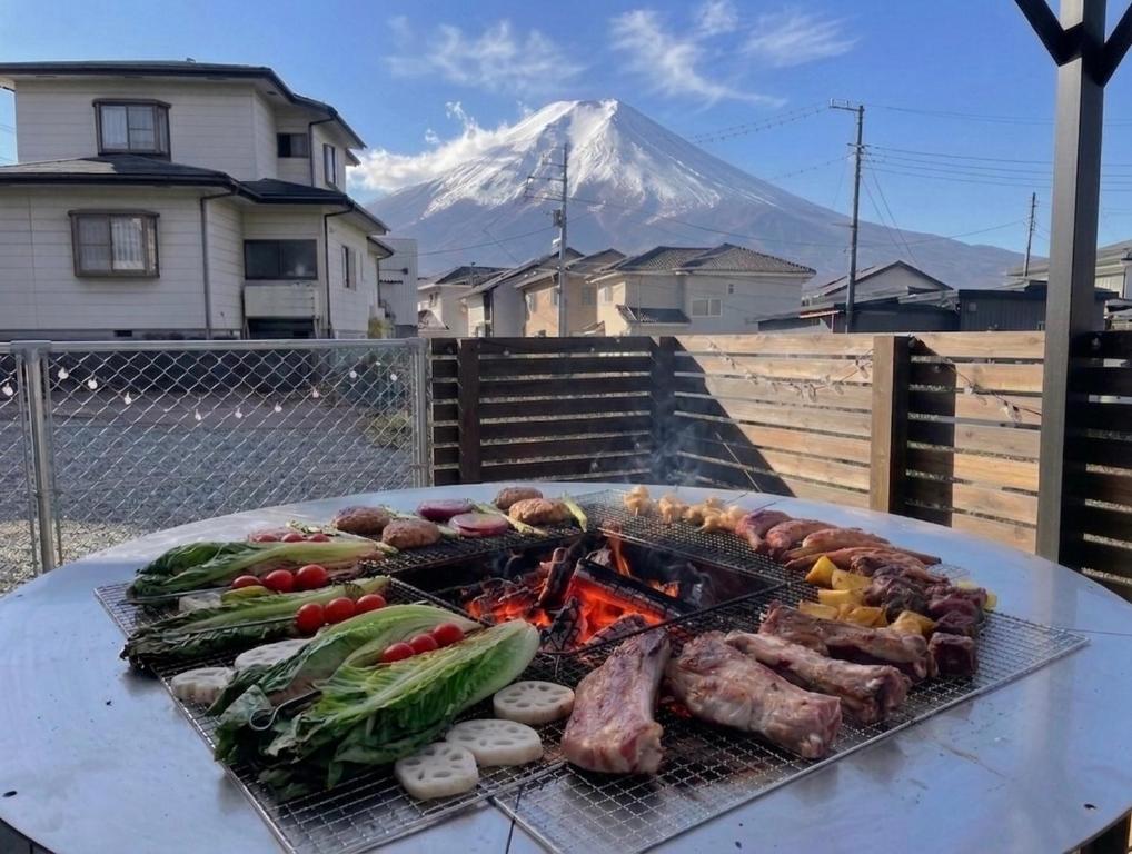 a grill with meat and vegetables on a table with a mountain at Villa Hello Fujisan ヴィラハローフジサン 屋根付きBBQ場 ワンちゃん大歓迎 A220 in Fujiyoshida