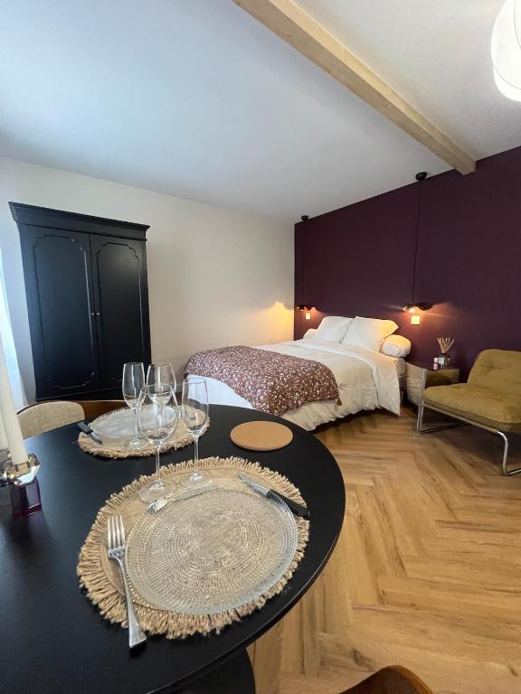 a room with a bed and a table with wine glasses at Nuit Céleste Studio élégant avec parking Centre Morteau in Morteau