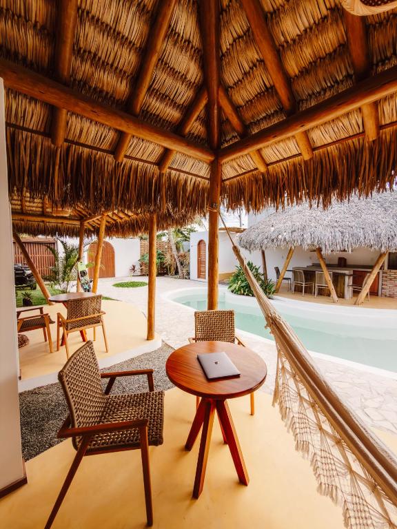 a hammock in a resort with a table and chairs at Villa Mia - Praia do Preá in Prea
