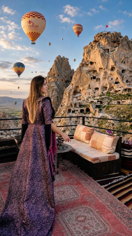 a woman standing next to a bed with hot air balloons at Duven Hotel Cappadocia in Uçhisar