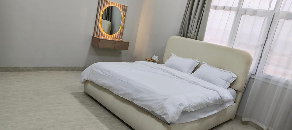a bedroom with a bed with white sheets and a mirror at فلل فاخرة للإيجار صلالة Salalah Villas in Salalah