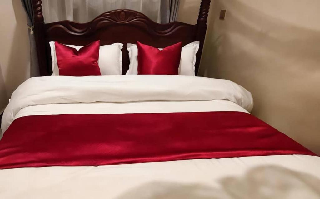 a red blanket laying on top of a bed with red pillows at Muzinge inn in Kagolomolo