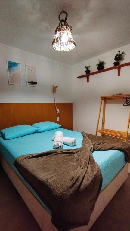 a bedroom with a bed with blue pillows and a light at Brisa da Mata suítes BF in Baía Formosa