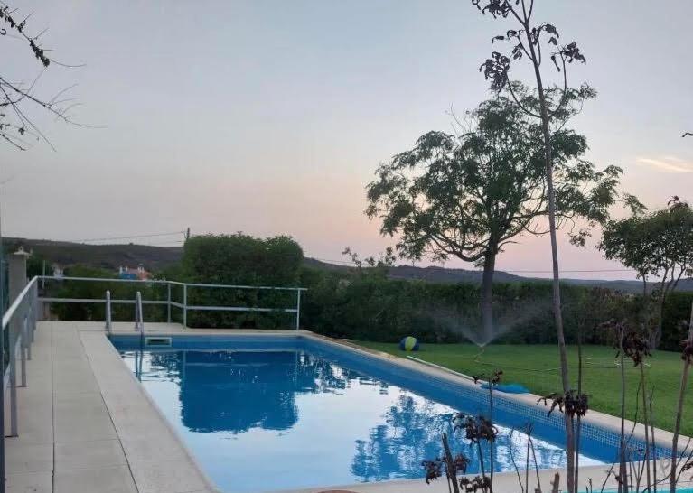 a large swimming pool in a yard with a tree at Casa Monte da Eira in Giões