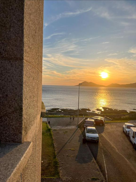 a sunset over the ocean with cars parked in a parking lot at Apartamento Son do Mar in Porto do Son