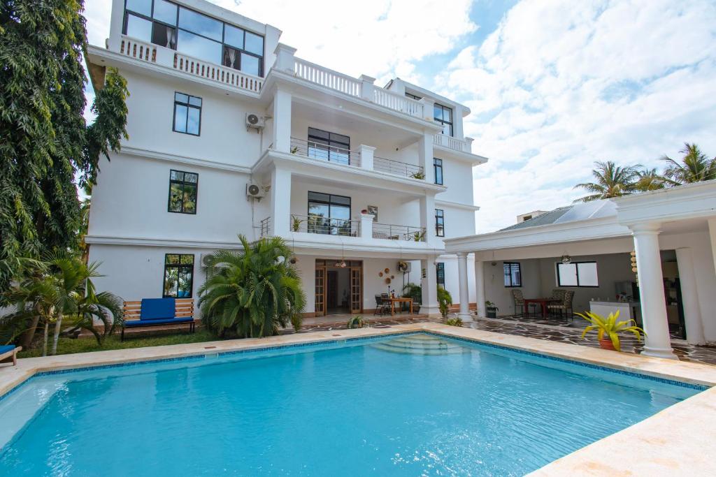 a large white house with a swimming pool in front of it at Dianiluxe Villa - Spacious studio 4 in Galu