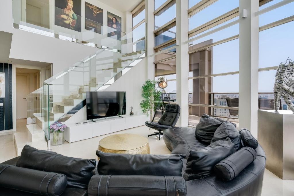 a living room with a leather couch and a tv at Penthouse Duplex with Epic Views in Barcelona