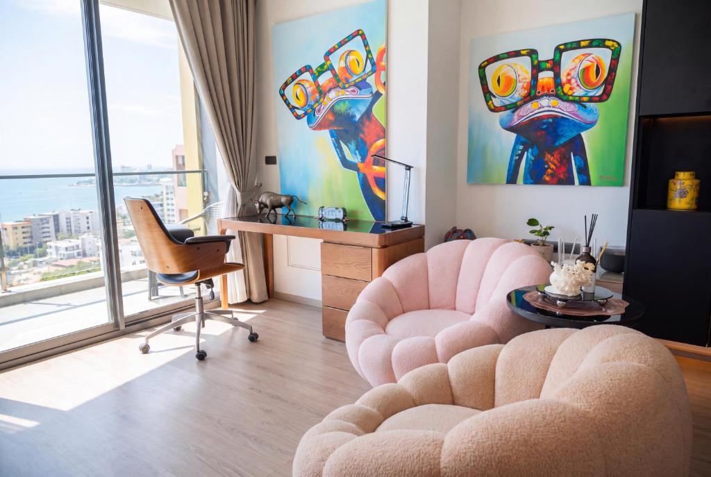 a living room with two chairs and a table and a painting at EDGE Central Pattaya 2BR Ocean View Luxury Condo Rooftop Pool Central Location in Pattaya
