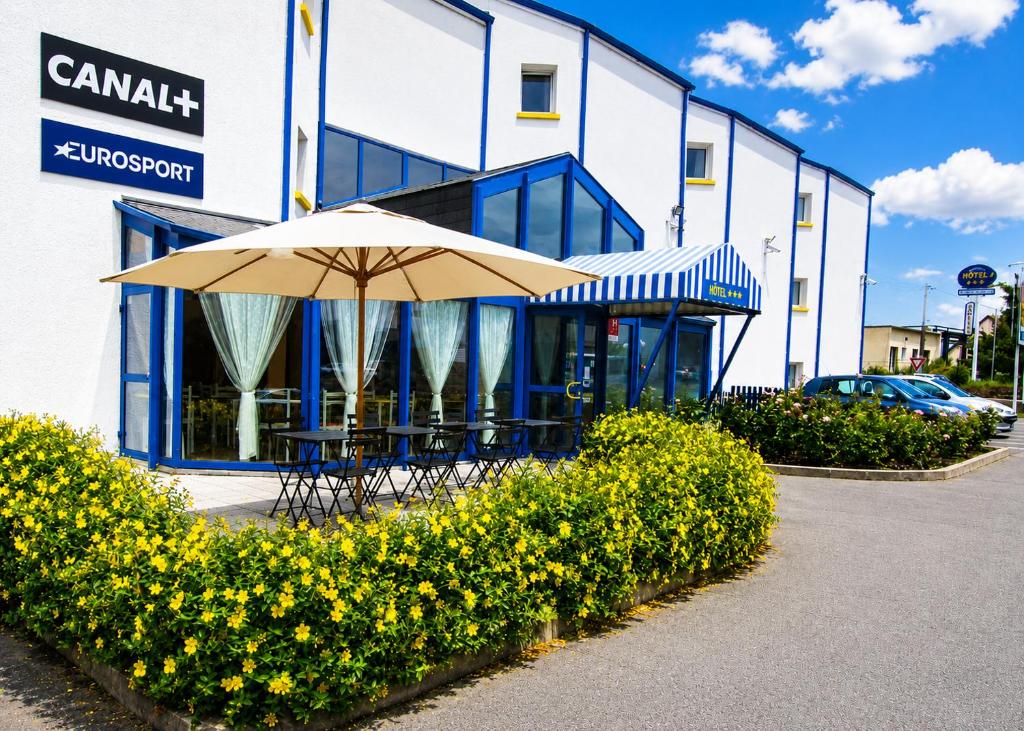 a table with an umbrella in front of a building at Hôtel Noctuel Blois Sud in Saint-Gervais-la-Forêt