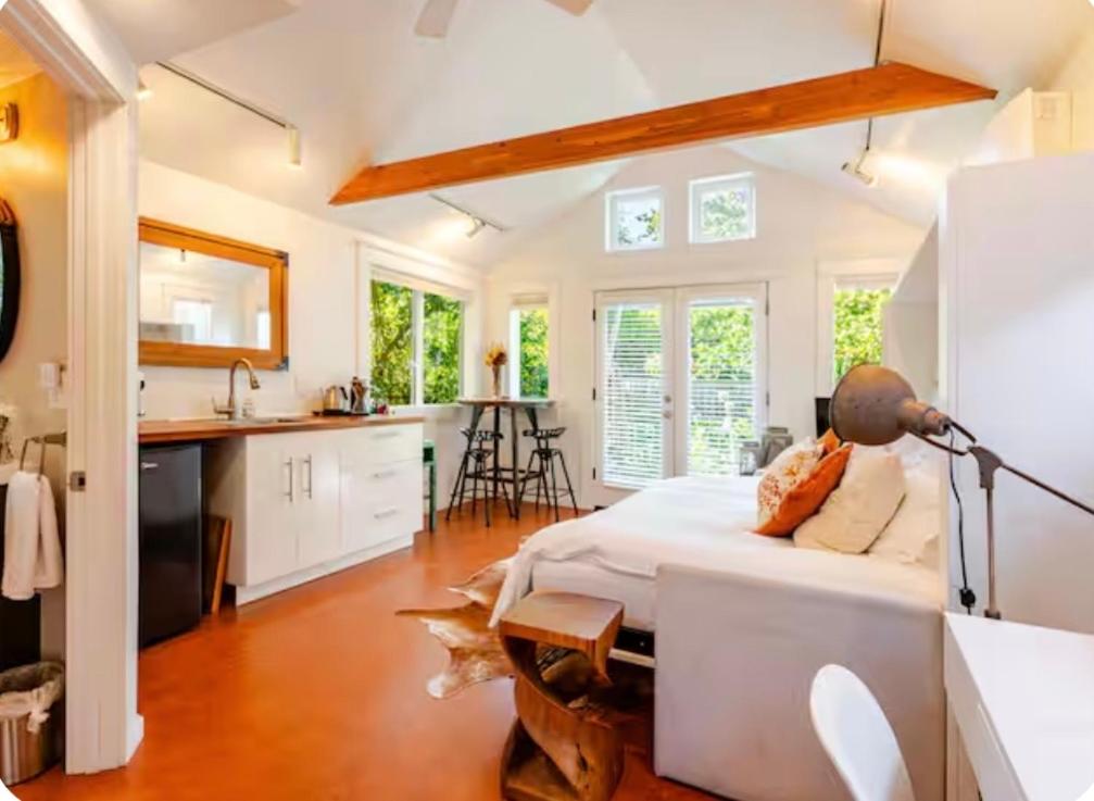 a white bedroom with a bed and a kitchen at Star Studio, A Garden Retreat near University of Oregon in Eugene