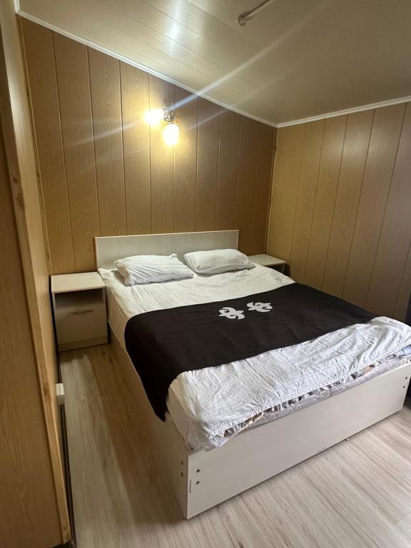 a bedroom with a bed with a black and white blanket at Green House in Karakol