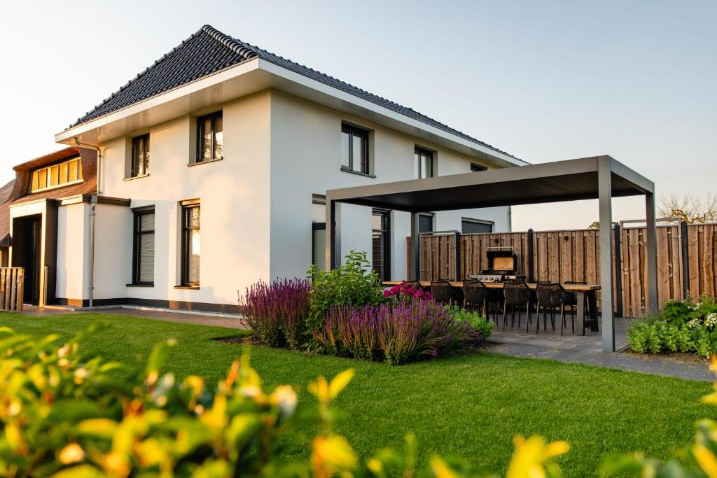 a house with a patio with a table in a yard at Luxe buitenhuis 10 pers met jacuzzi en vrij uitzicht in Rheeze
