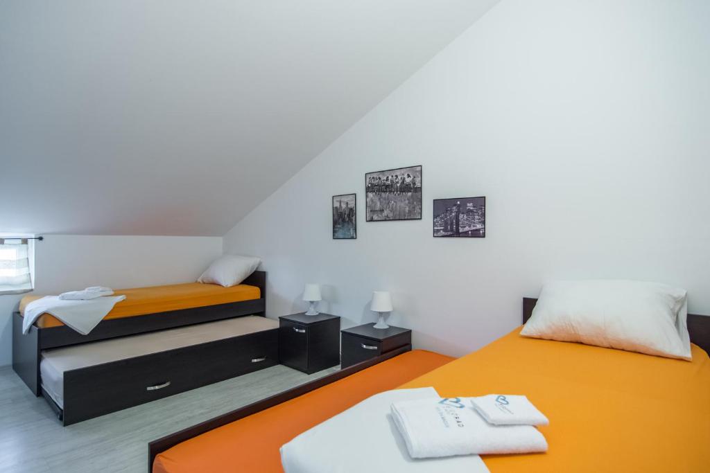 dwa łóżka w pokoju pomarańczowo-białym w obiekcie Apartments Domuzin w Biogradzie na Moru