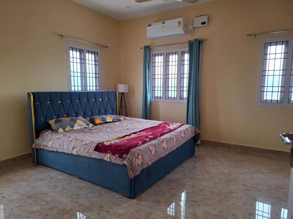 a bedroom with a blue bed in a room with windows at Malliga Farm House in Turinjāpuram