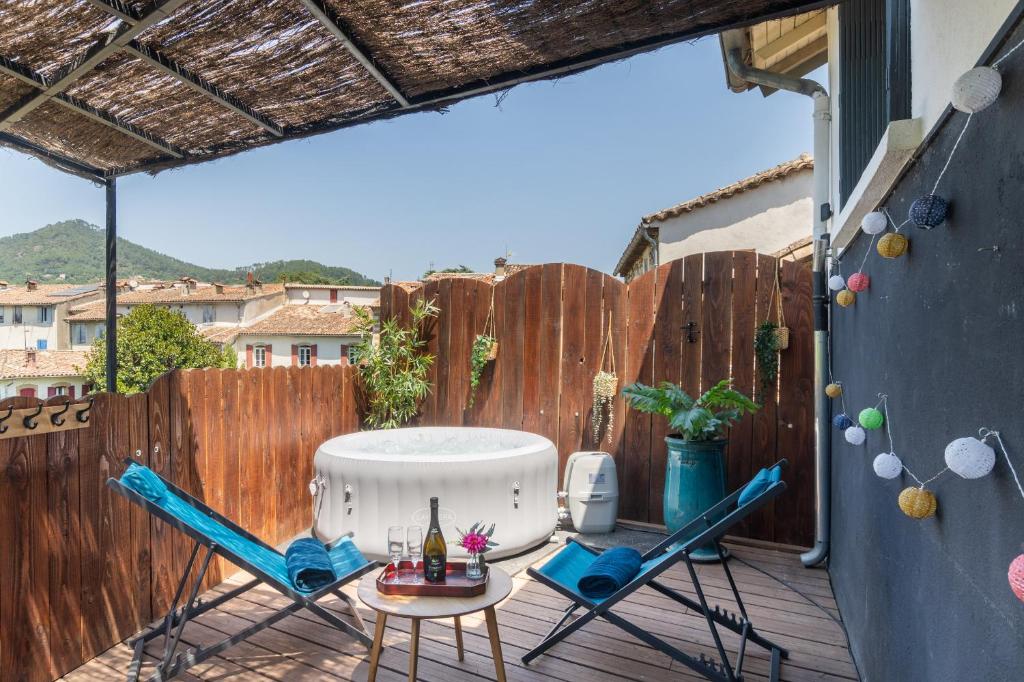 a patio with two chairs and a table on a fence at Duplex Terrasse Jacuzzi Privatif & Vue Cévennes in Saint-Jean-du-Gard