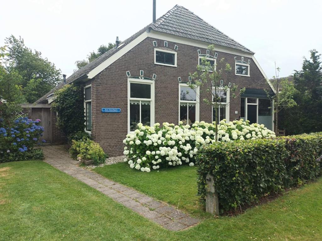a brick house with white flowers in the yard at Het Voorhuis in Grolloo