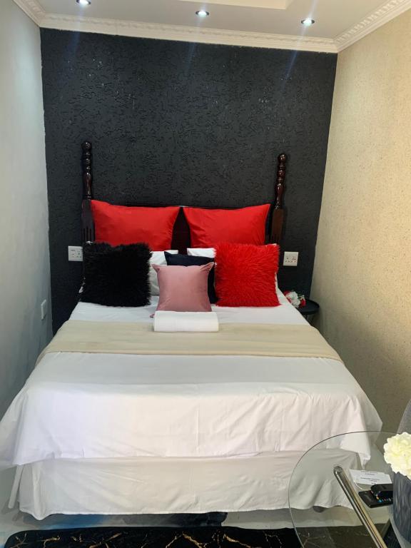 a bedroom with a bed with red and black pillows at Ecogreen on OR Tambo in Kempton Park