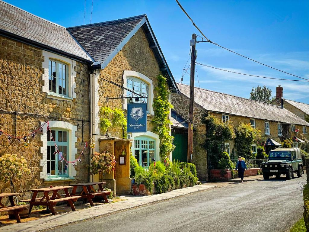 a building with picnic tables on the side of a street at The Barrington Boar in Ilminster