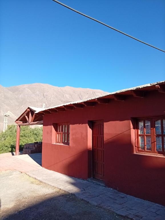 a red building with a mountain in the background at Maimara Hospedaje Sumalawa in Maimará