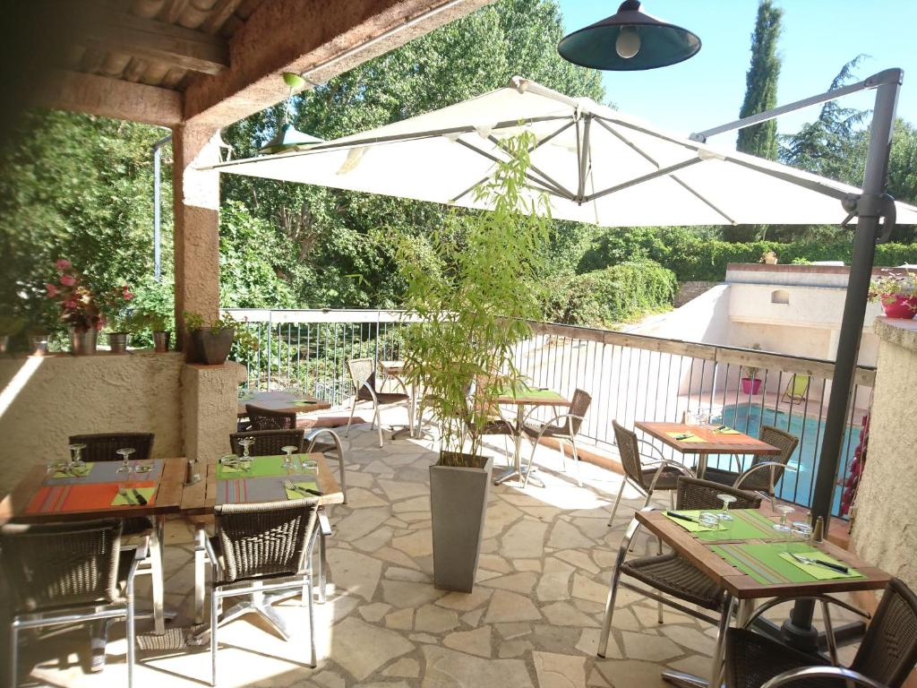 a patio with tables and chairs and an umbrella at Lou Cigaloun in Saint Antonin du Var