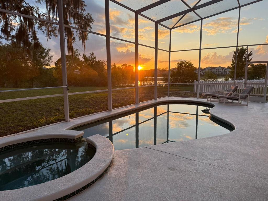 a swimming pool in front of a building with a sunset at Villa With Private Pool, and Lake Views in Davenport