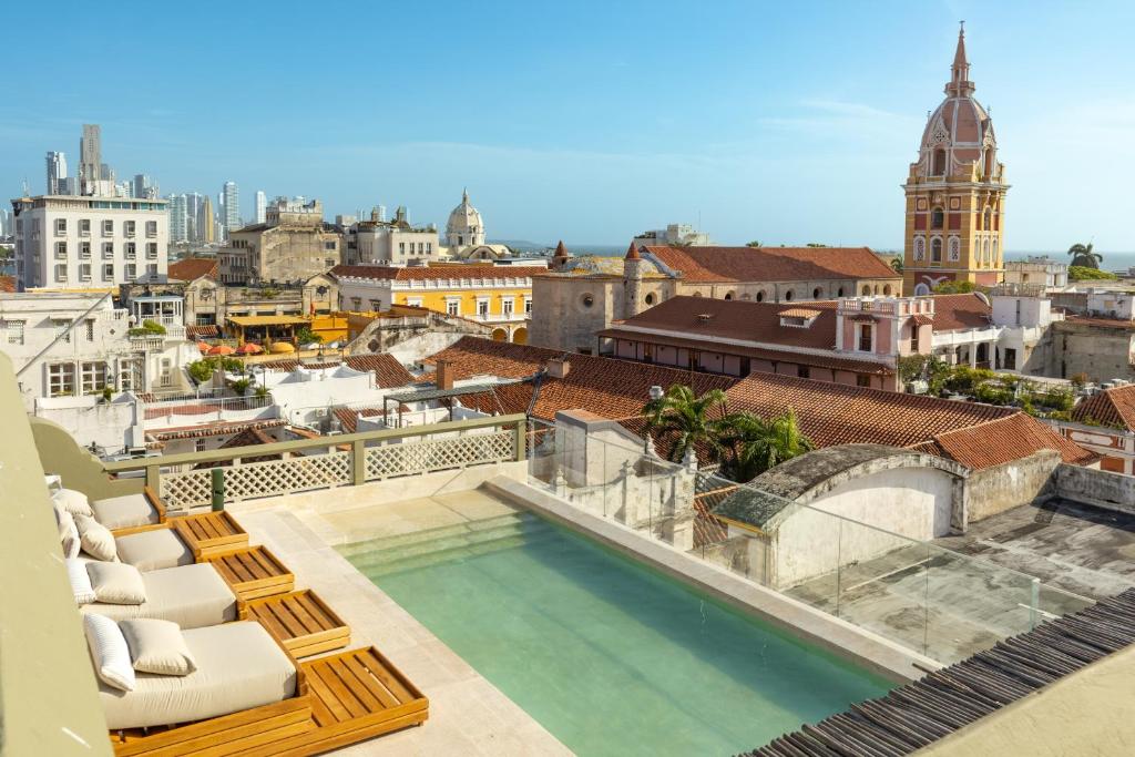 a pool on the roof of a building with chairs at Hotel El Balconario by Faranda Boutique in Cartagena de Indias