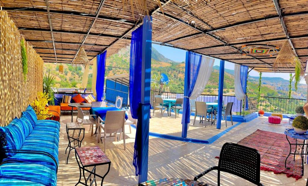 a patio with a blue couch and tables and chairs at Dar Besmellah in Chefchaouen