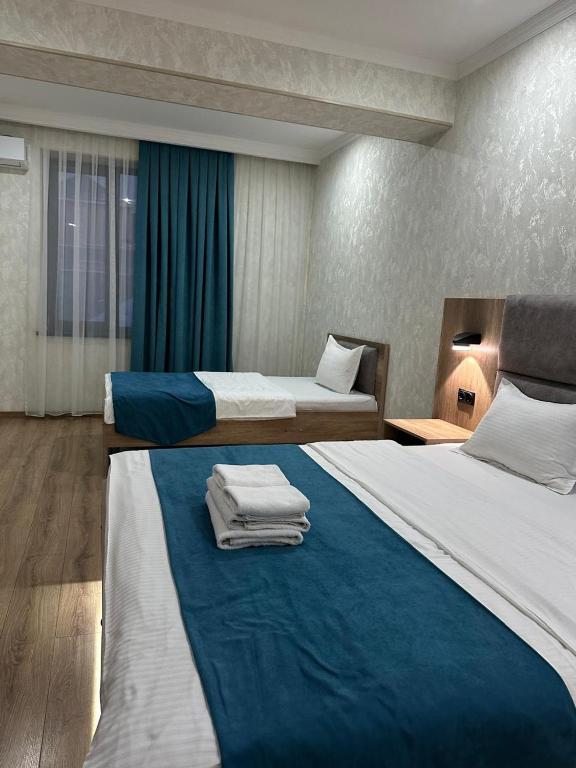 a hotel room with two beds with towels on them at Palace&Spa Rooms in Shymkent