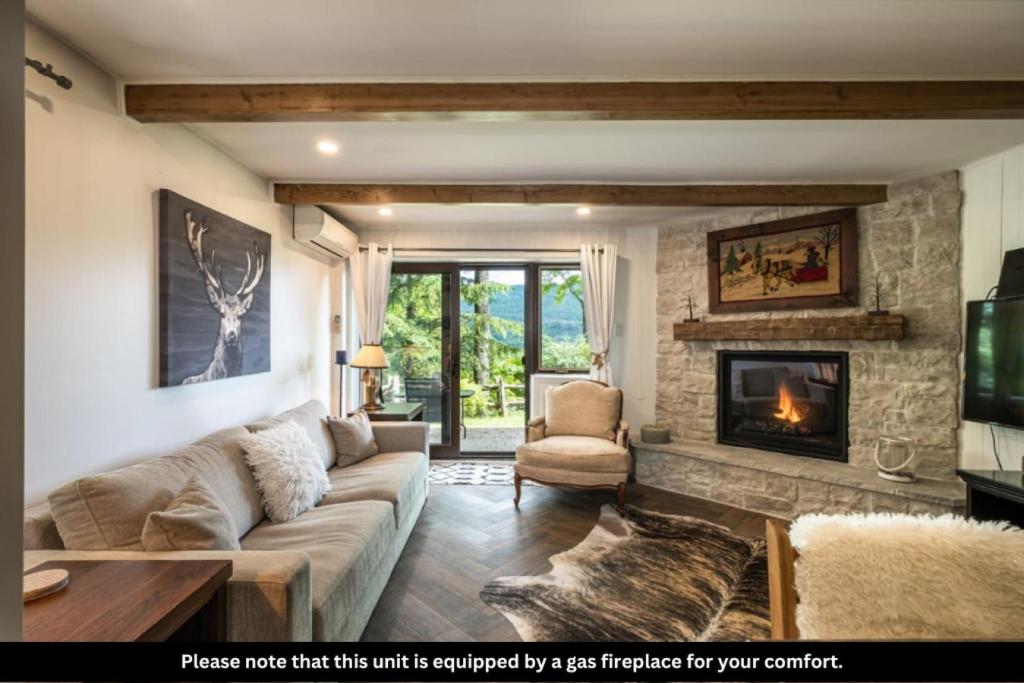 a living room with a couch and a fireplace at Simple & Luxe Condo With View in Mont-Tremblant