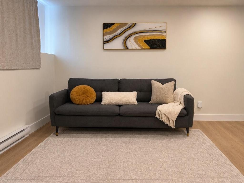 a gray couch in a living room with a painting at Modern Riverview Suite Near Downtown Moncton in Riverview